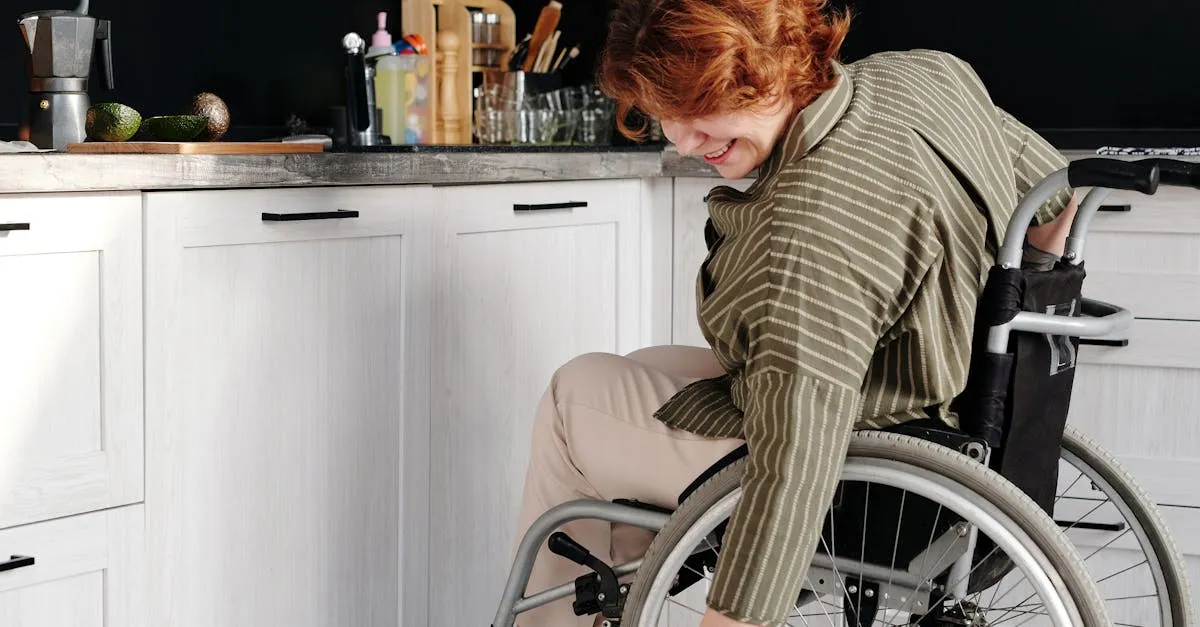 A woman in a wheelchair smiles while petting a tabby cat in a modern kitchen.